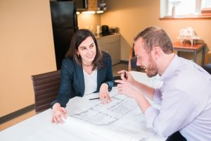 Two employees talking over architectural plans